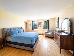 A bedroom with a large bed, a dresser, a chair, and a window with curtains. - Renovated, Five Bedrooms In Historic Williamstown (Williamstown)