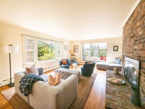 A spacious living room with a fireplace, large windows, and a cozy seating area.