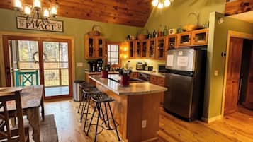 A kitchen with wooden floors, a bar area, and a ceiling fan.
