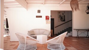 A modern interior with wicker chairs, a sofa, a staircase, and a 'Welcome' sign. - Le M Hotel Marie Galante (Capesterre-de-Marie-Galante)