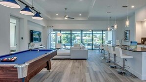 A modern kitchen with white cabinets, a built-in microwave, and a dining area with bar stools. - VRCC Villa Skyfall (Cape Coral)