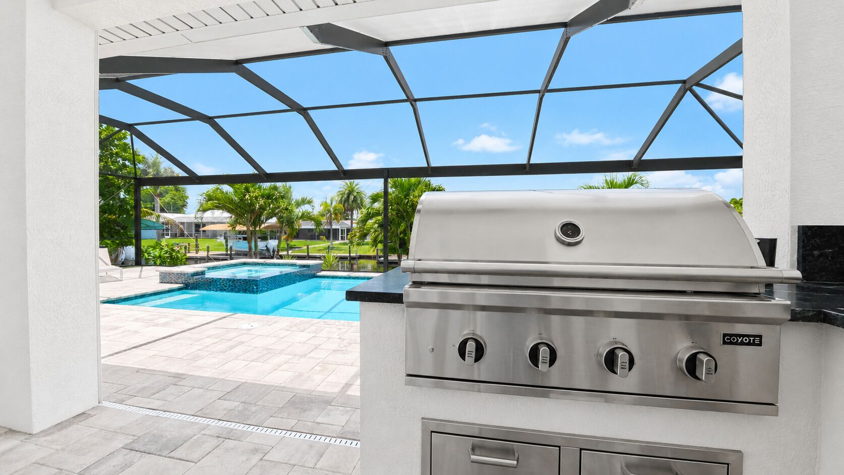 Eine Terrasse mit Grill, Swimmingpool und Blick auf eine Wohngegend.