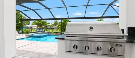 Eine Terrasse mit Grill, Swimmingpool und Blick auf eine Wohngegend.