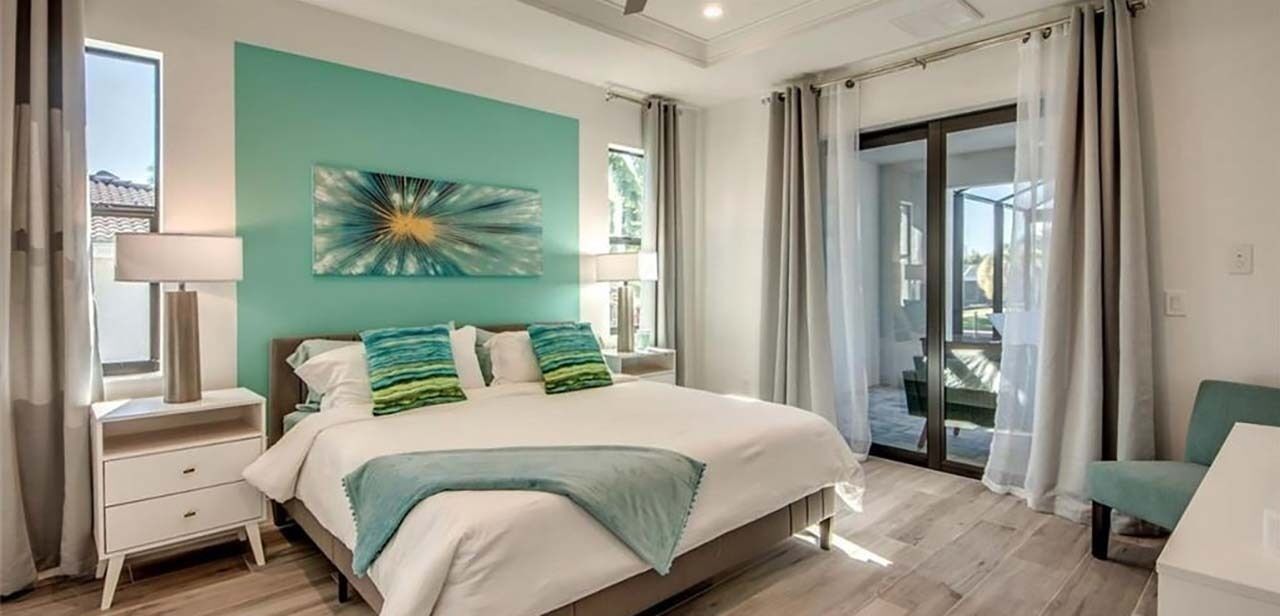 Une chambre à coucher comprenant un lit, une table de chevet, une lampe et une vue sur l’extérieur grâce à une porte coulissante.