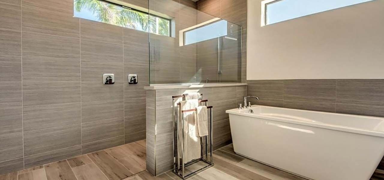 A modern bathroom with a glass shower enclosure, a freestanding bathtub, and a large mirror.