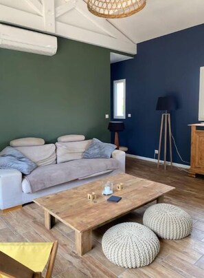 A modern living room with a sofa, coffee table, and ottomans.
