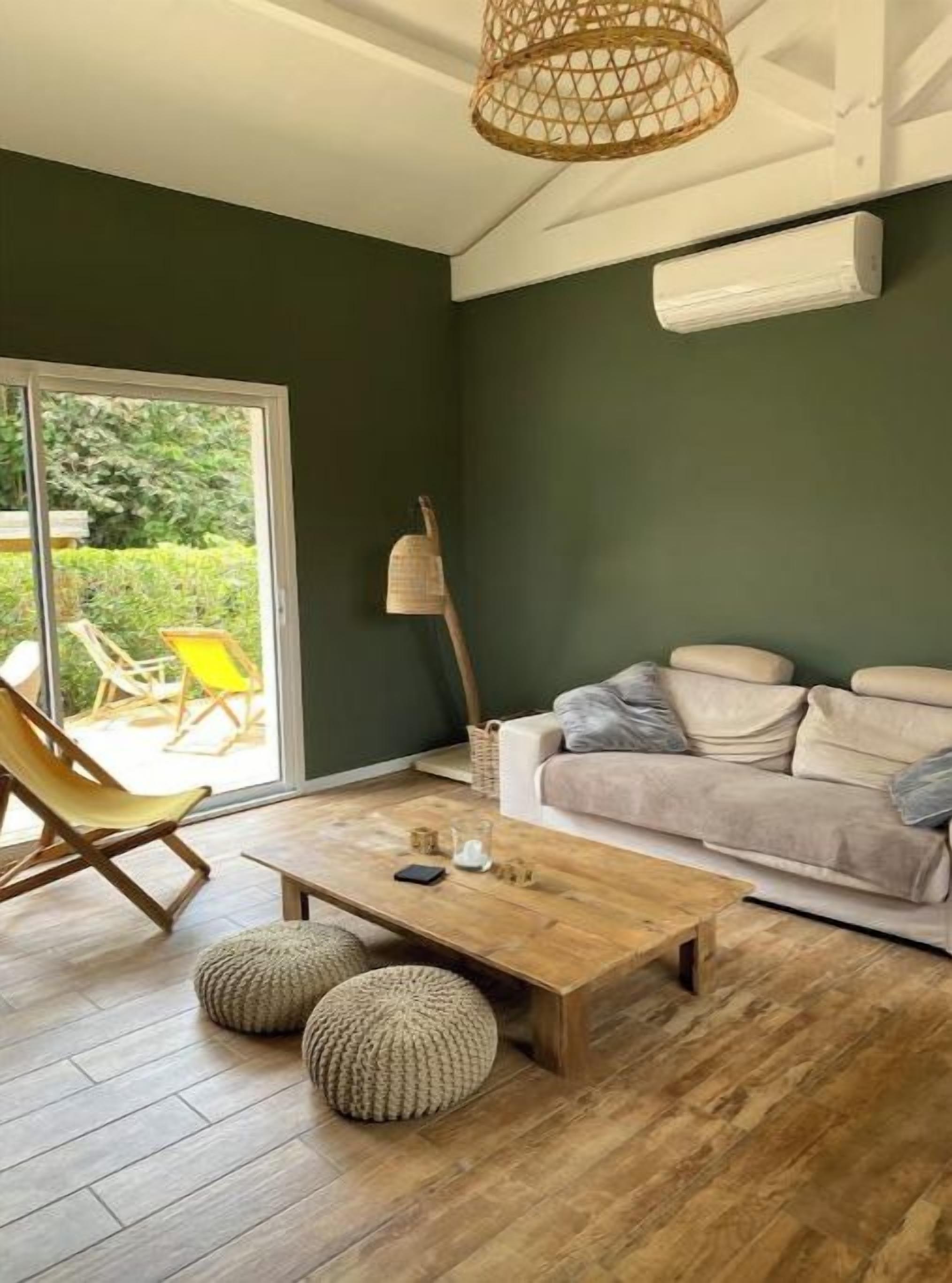 Un salon avec un plancher en bois, un canapé, une table basse et un fauteuil en osier.