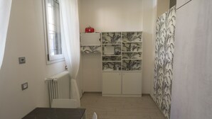 A compact kitchen with white cabinets, a radiator, and a window.