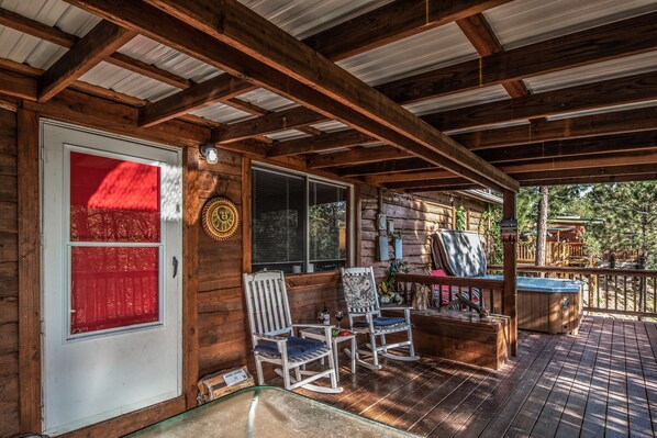 A wooden deck with rocking chairs and a hot tub.