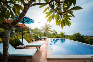 Una piscina al aire libre, sombrillas, sillones reclinables de piscina