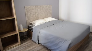 Ein Schlafzimmer mit einem Bett, einem Nachttisch aus Holz, einem runden Beistelltisch und einer eingebauten Regallösung.