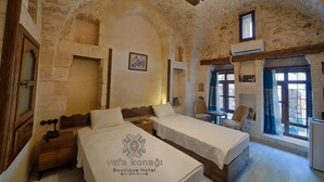 Una habitación con dos camas, muebles de madera, paredes de piedra y vistas amplias a través de grandes ventanas.