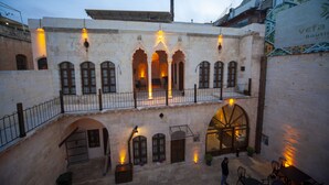 Un patio con un edificio de piedra que presenta puertas en arco y un balcón.