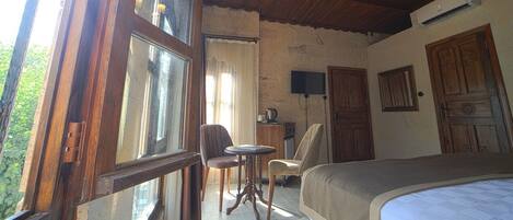 Ein Schlafzimmer mit einem Bett, einem Sessel, einem kleinen Tisch, einem Fernseher und einer Holztür.