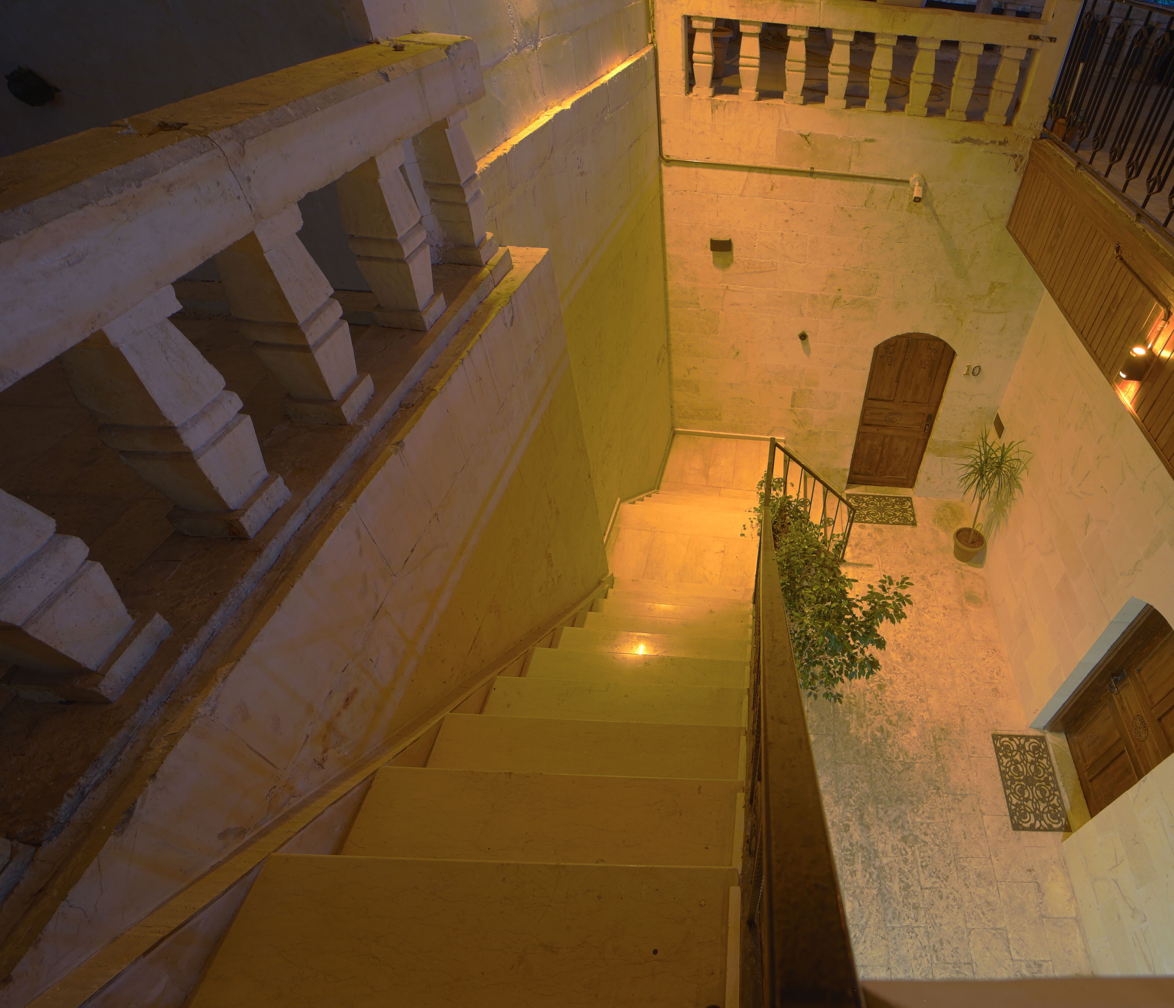 A staircase leading to a courtyard with a wooden door and a potted plant.