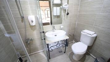 Un baño con cabina de ducha de vidrio, un lavabo blanco, un inodoro y un espejo.