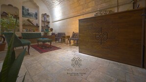 Un interior tradicional con paredes de piedra, un mostrador de recepción de madera y un sofá verde.