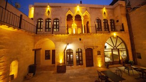 Un patio con zona de comedor, muros de piedra y puertas arqueadas.