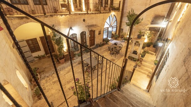 Un interior de varios niveles con una escalera, plantas en macetas y una zona de comedor.