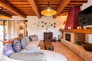 Una sala de estar acogedora con techo de madera, chimenea y un sofá con cojines a rayas.