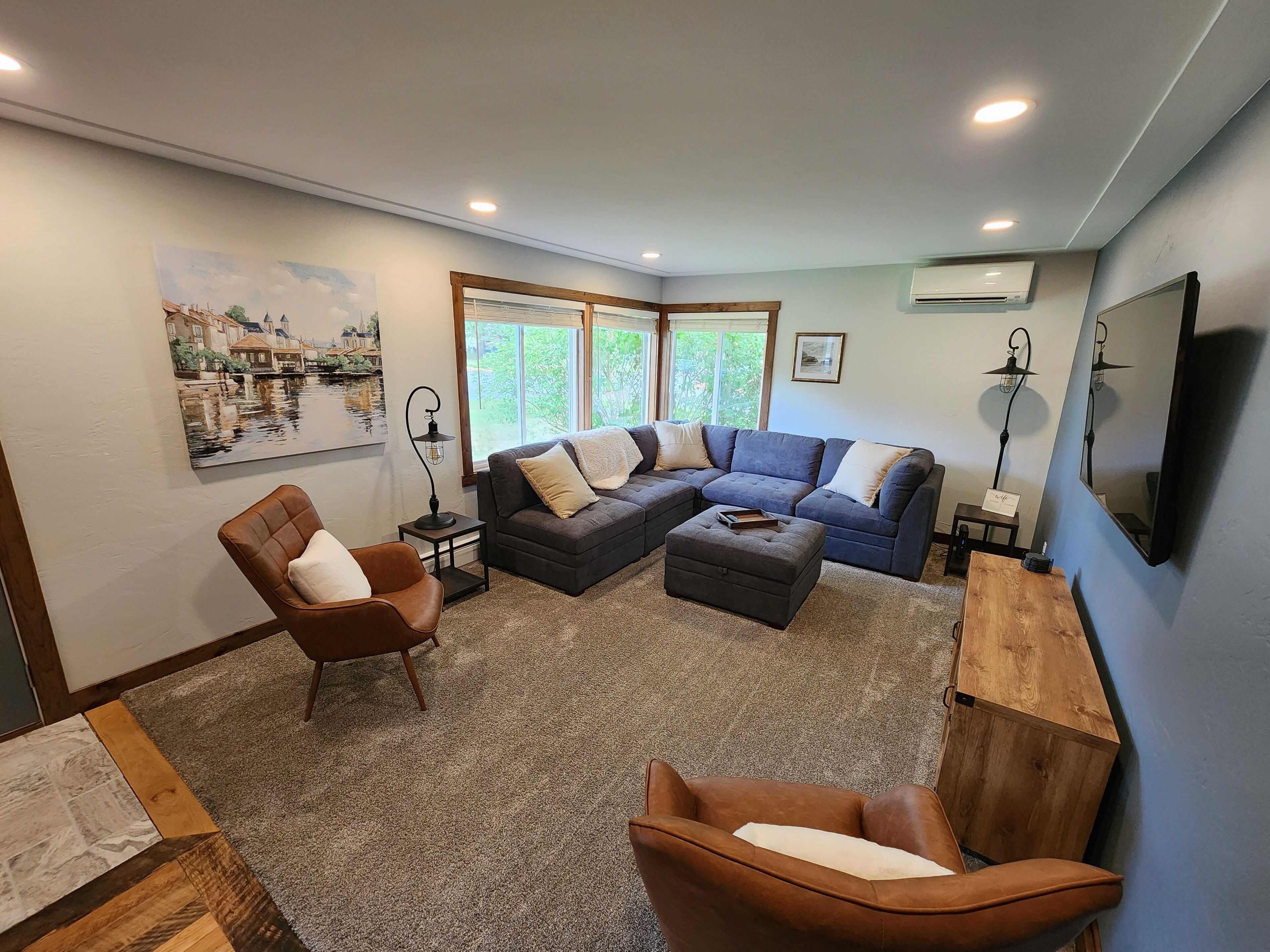 Uma sala de estar com sofá modular, duas poltronas, uma mesa de centro e um aparador de madeira.