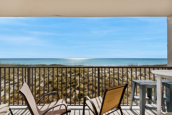 A balcony with a view of the beach and ocean.