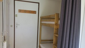 Quarto com beliche, porta de madeira e maçaneta.