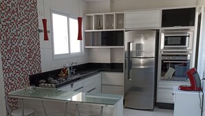 A modern kitchen with a central island, stainless steel appliances, and a red pendant light. - Gorgeous appartement in condominium club (São José dos Campos)