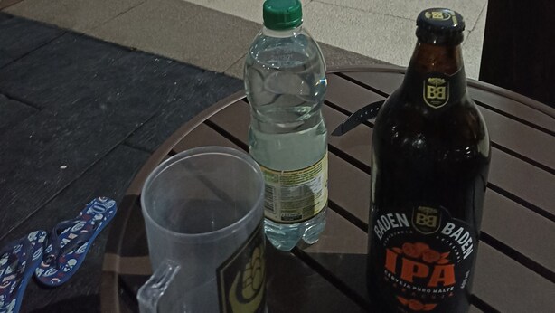 A poolside table with a bottle of beer, a water bottle, and flip-flops. - Gorgeous appartement in condominium club (São José dos Campos)
