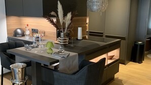 Una cocina moderna con una isla central, armarios oscuros y una lámpara de cristal colgante.