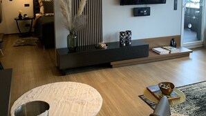 Una sala de estar moderna con un televisor de pantalla plana, una consola oscura y una mesa redonda de centro.