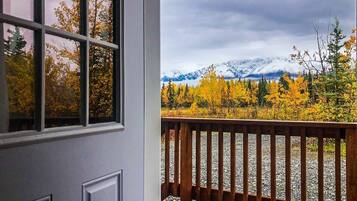 A wooden deck with a view of a mountainous landscape and autumn foliage.