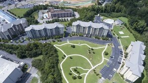 Eine Vogelperspektive auf einen Wohnkomplex mit mehreren Mehrfamilienhäusern, einer begrünten Grünfläche im Zentrum und einem Parkplatz.