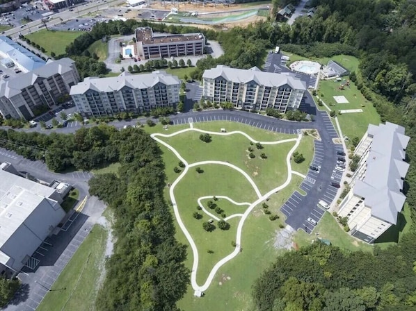 An aerial view of a residential complex with multiple apartment buildings, a central landscaped area, and a parking lot.