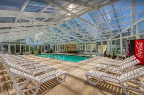 A covered pool area with lounge chairs and a Coca-Cola refrigerator.