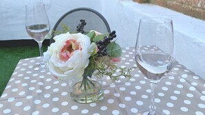 Een tafel met een tafelkleed met stippen, een vaas met een bloemstuk en twee wijnglazen.