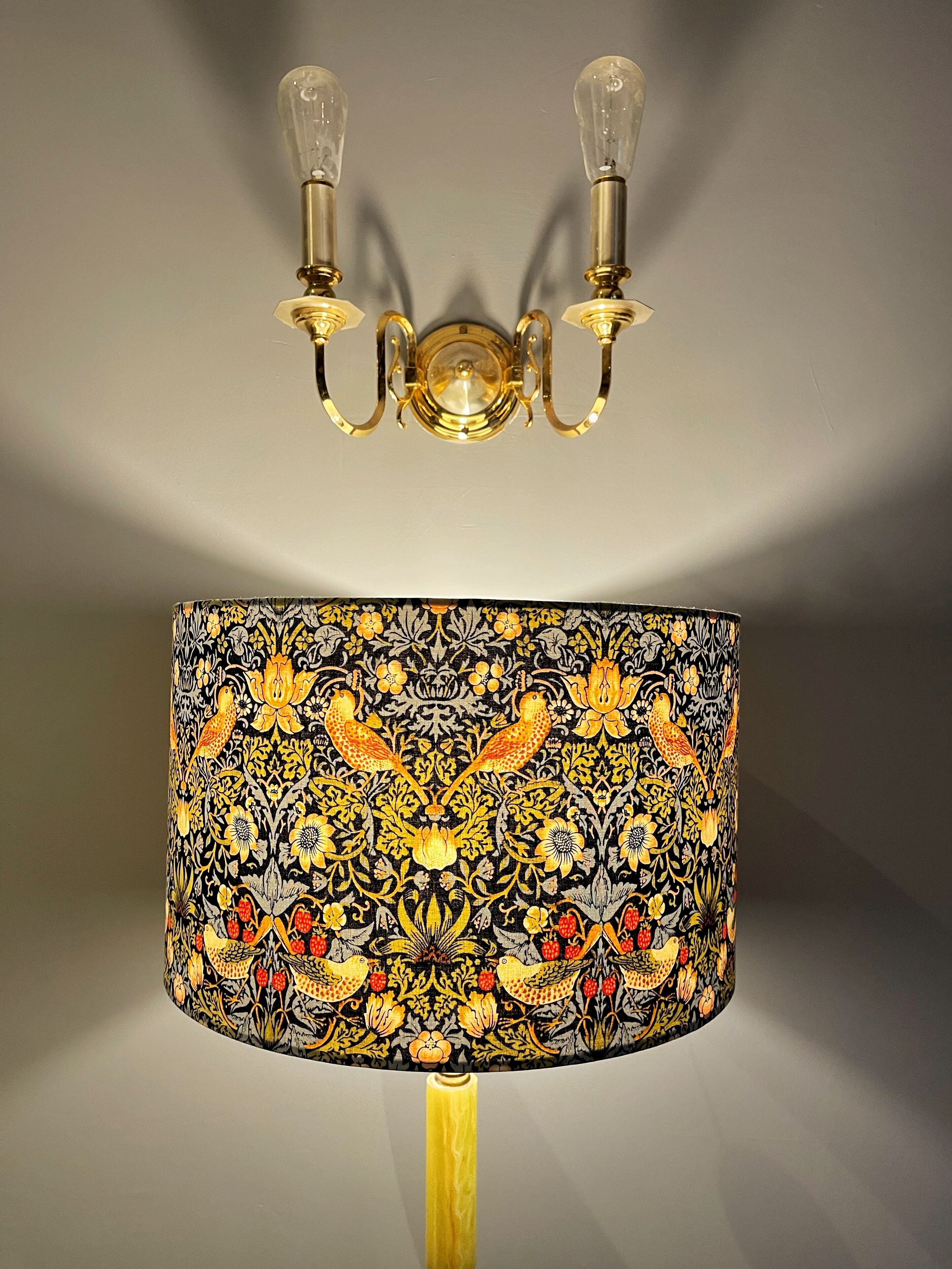 Une lampe dotée d’un abat-jour orné de motifs représentant des oiseaux et des fleurs.