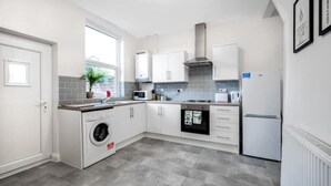 Een moderne keuken met witte kasten, een ingebouwde wasmachine, een magnetron en een fornuis.