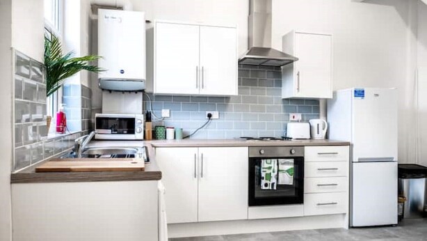 Een moderne keuken met witte kastjes, een magnetron, oven en koelkast.