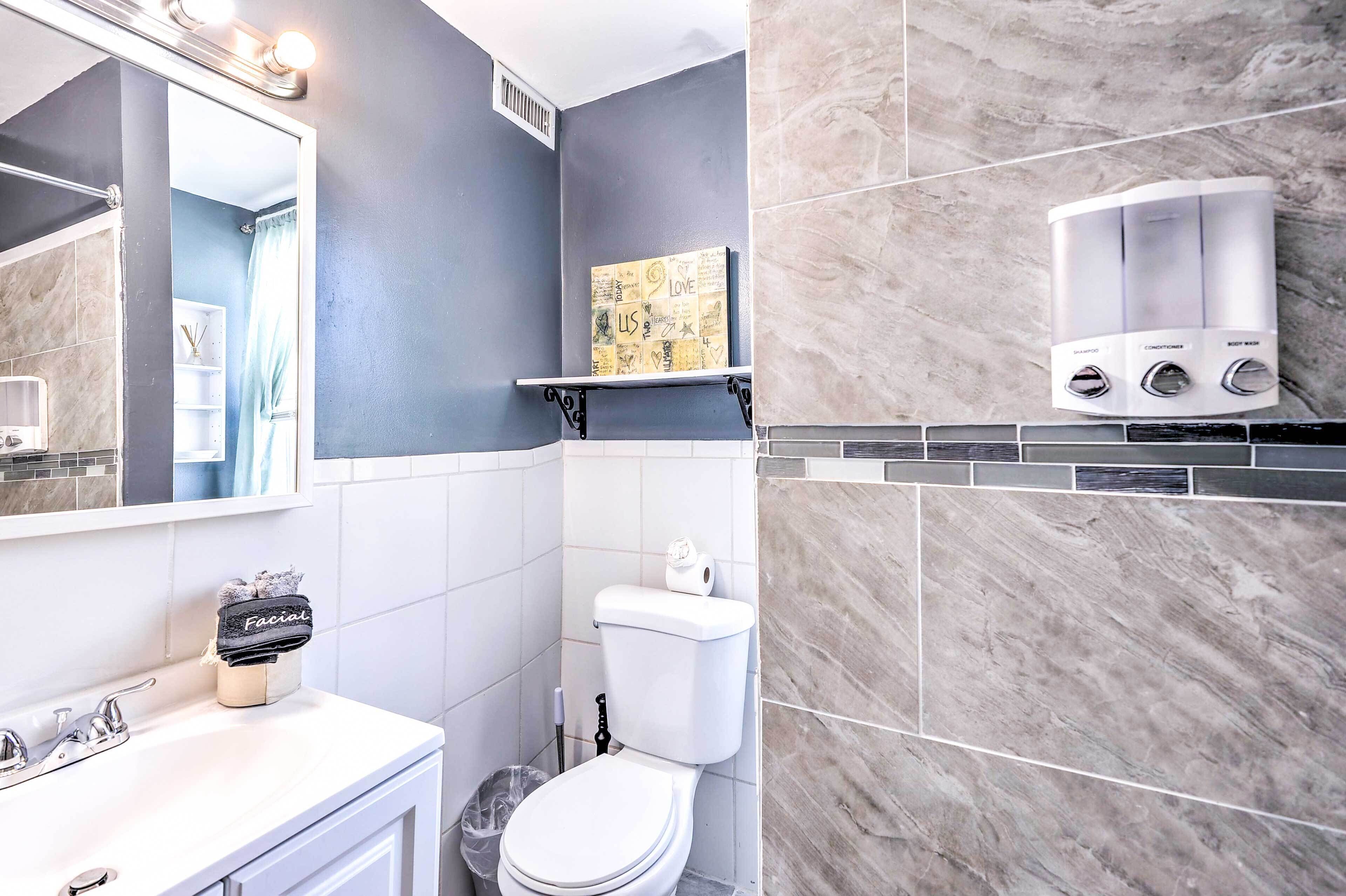 A bathroom with a white toilet, a sink with a faucet, a mirror, and a shelf with a decorative item.