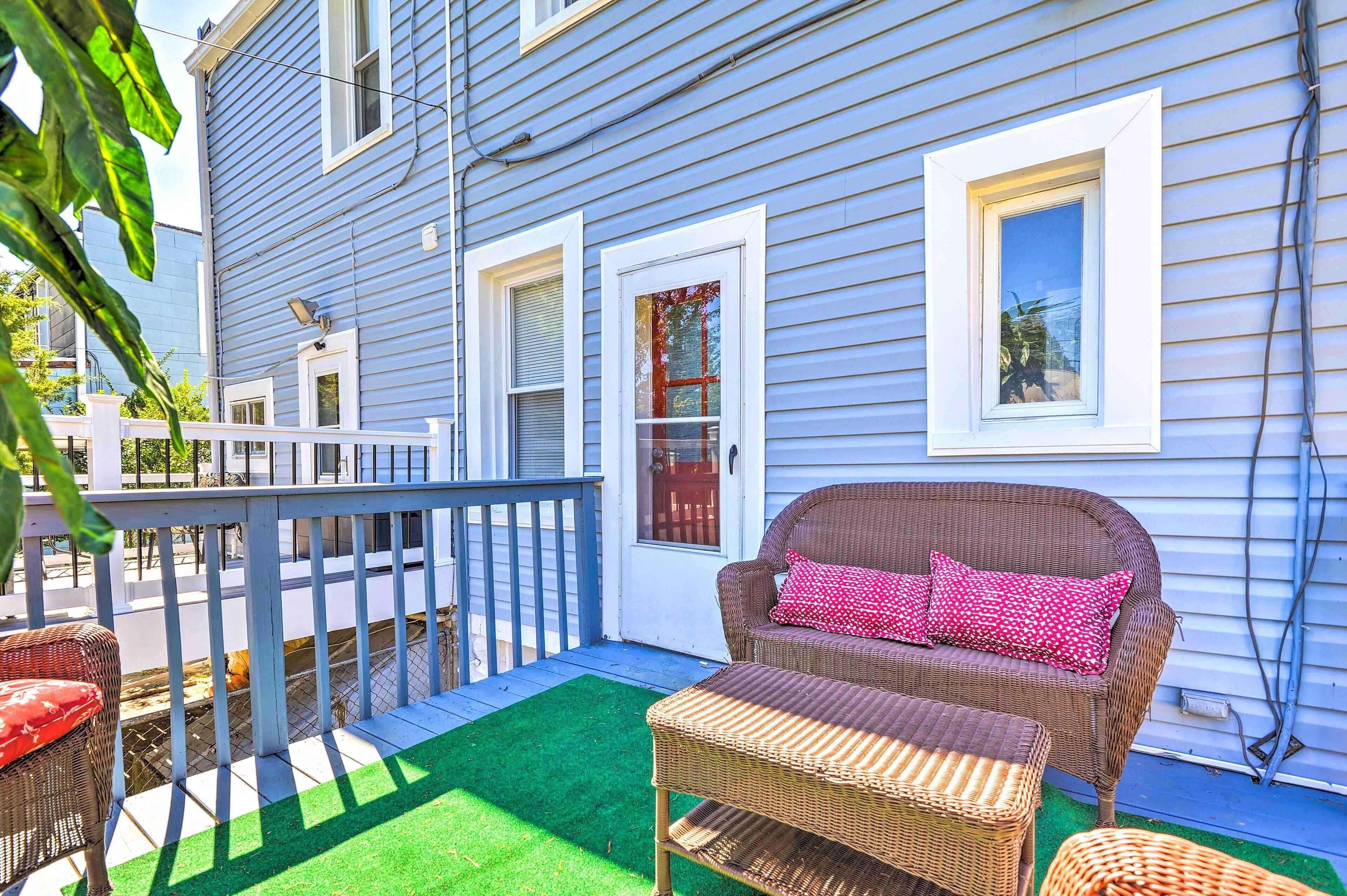 A blue house with a porch, wicker furniture, and a green lawn.