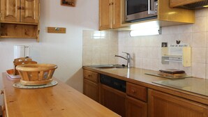 A kitchen with wooden cabinets, a microwave, a sink, and a wooden table with chairs.