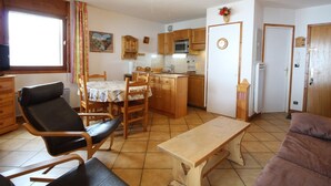 A compact living space with a dining area, a kitchenette, and a seating area with a sofa and chairs.