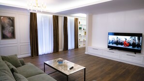Un salon moderne avec un téléviseur à écran plat, un canapé, une table basse et un lustre.