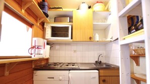 Ett kompakt kök med träskåp, en mikrovågsugn, en spis och en diskmaskin.
