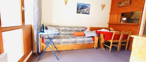 A cozy room with a sofa, a small table, and a wooden cabinet.
