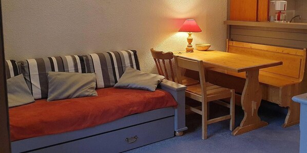 Une pièce chaleureuse avec un canapé à rayures, une table en bois et une lampe.