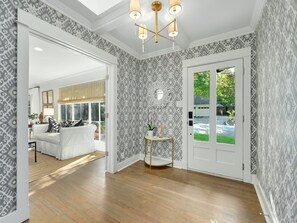 Enter a stylish space with a geometric patterned wall, white sofa, and modern chandelier.