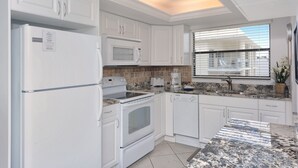 Una cocina moderna con armarios blancos, horno empotrado, microondas y lavavajillas.
