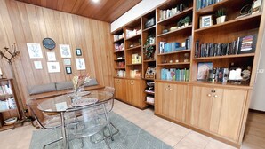 A room with a glass-top dining table, wooden bookshelves, and a clock on the wall. - La Mansardina (Roma)